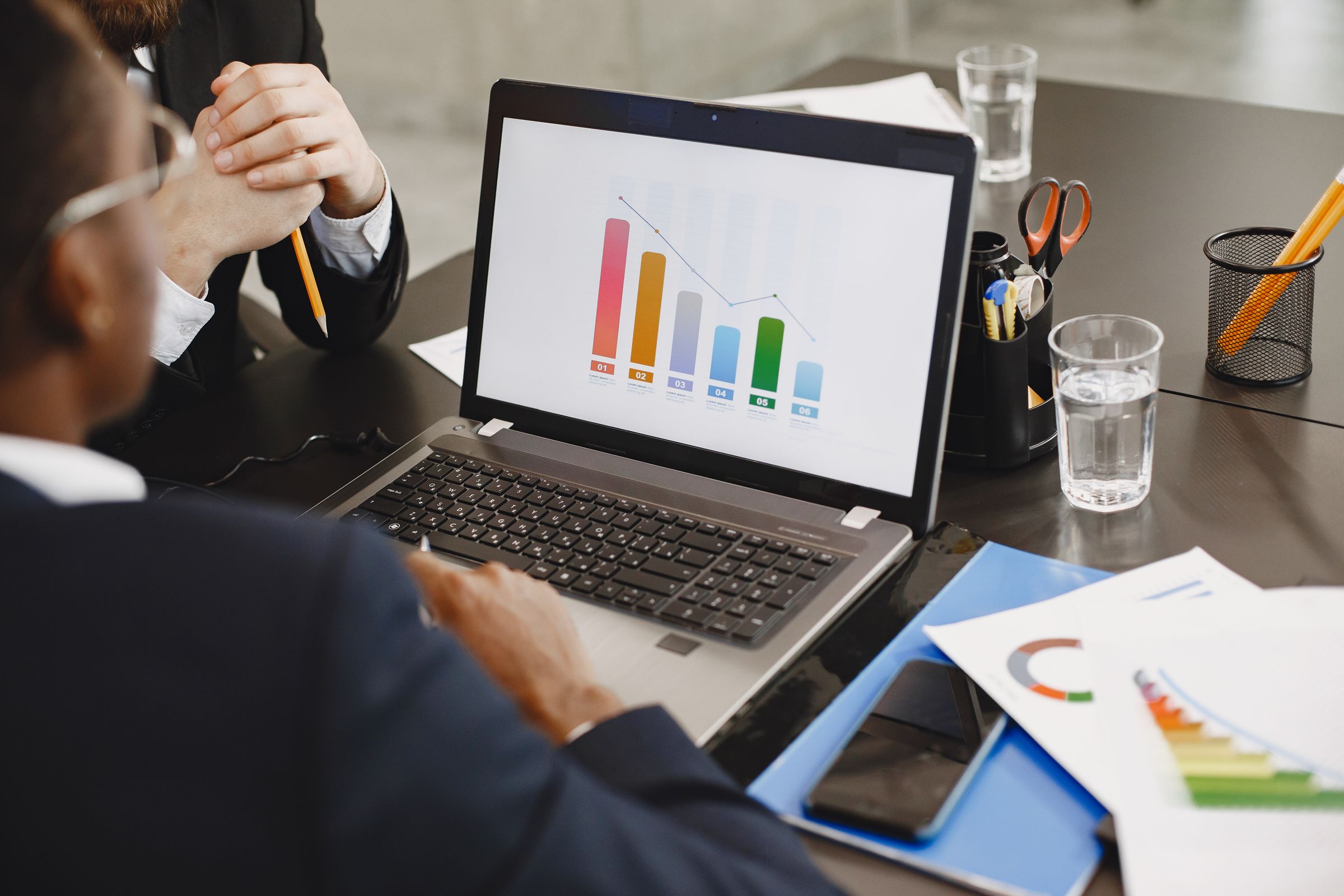 Professionals reviewing financial graphs on a laptop in an office