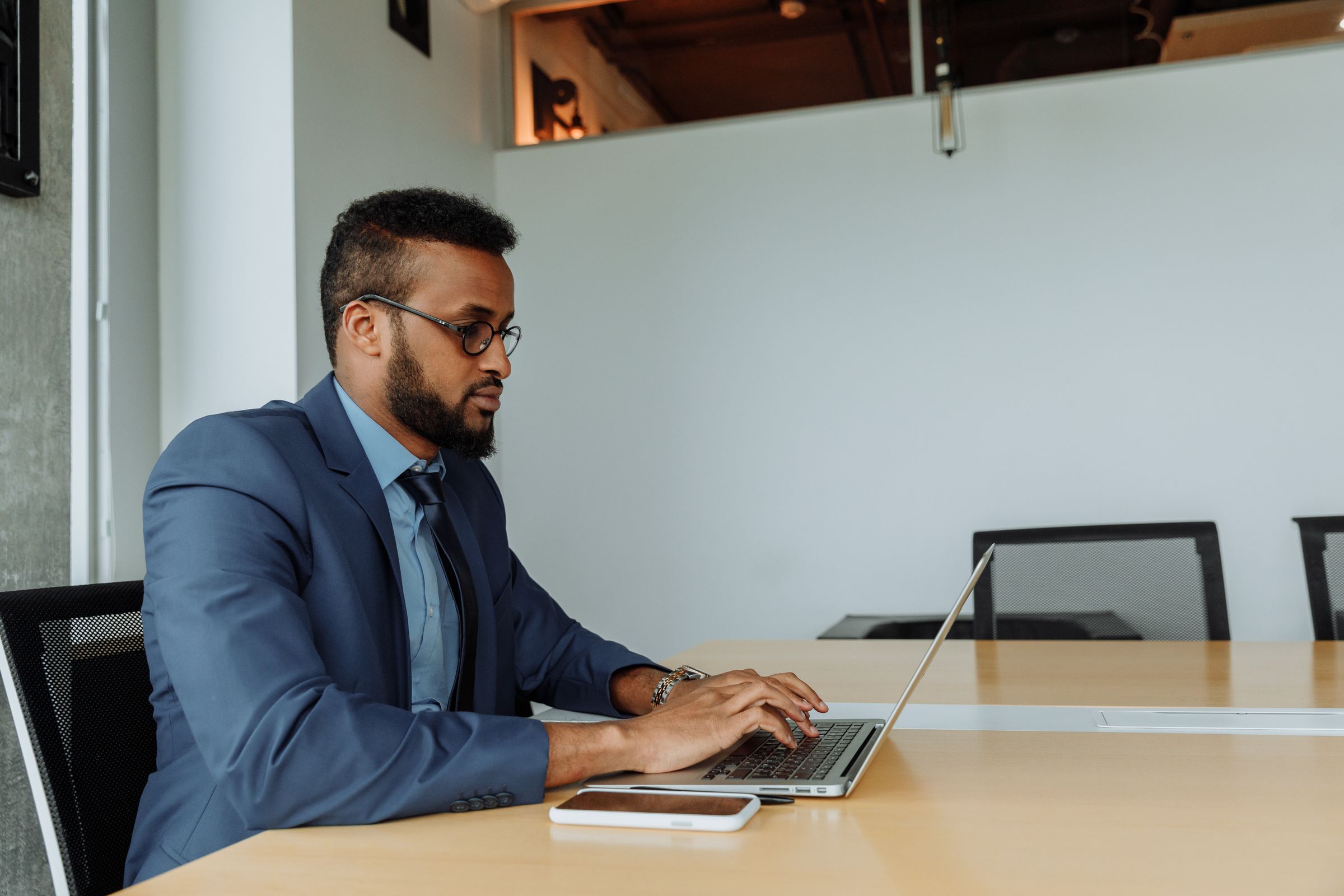 Business professional in a navy suit working at a laptop in a modern office