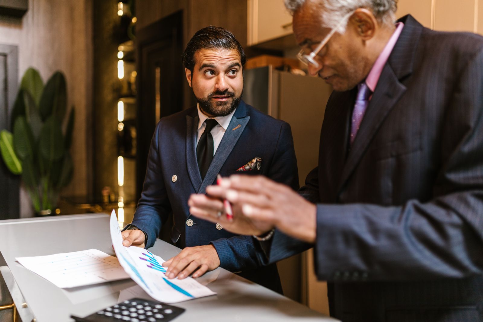 Two business advisors reviewing a printed bar chart and calculator at a counter