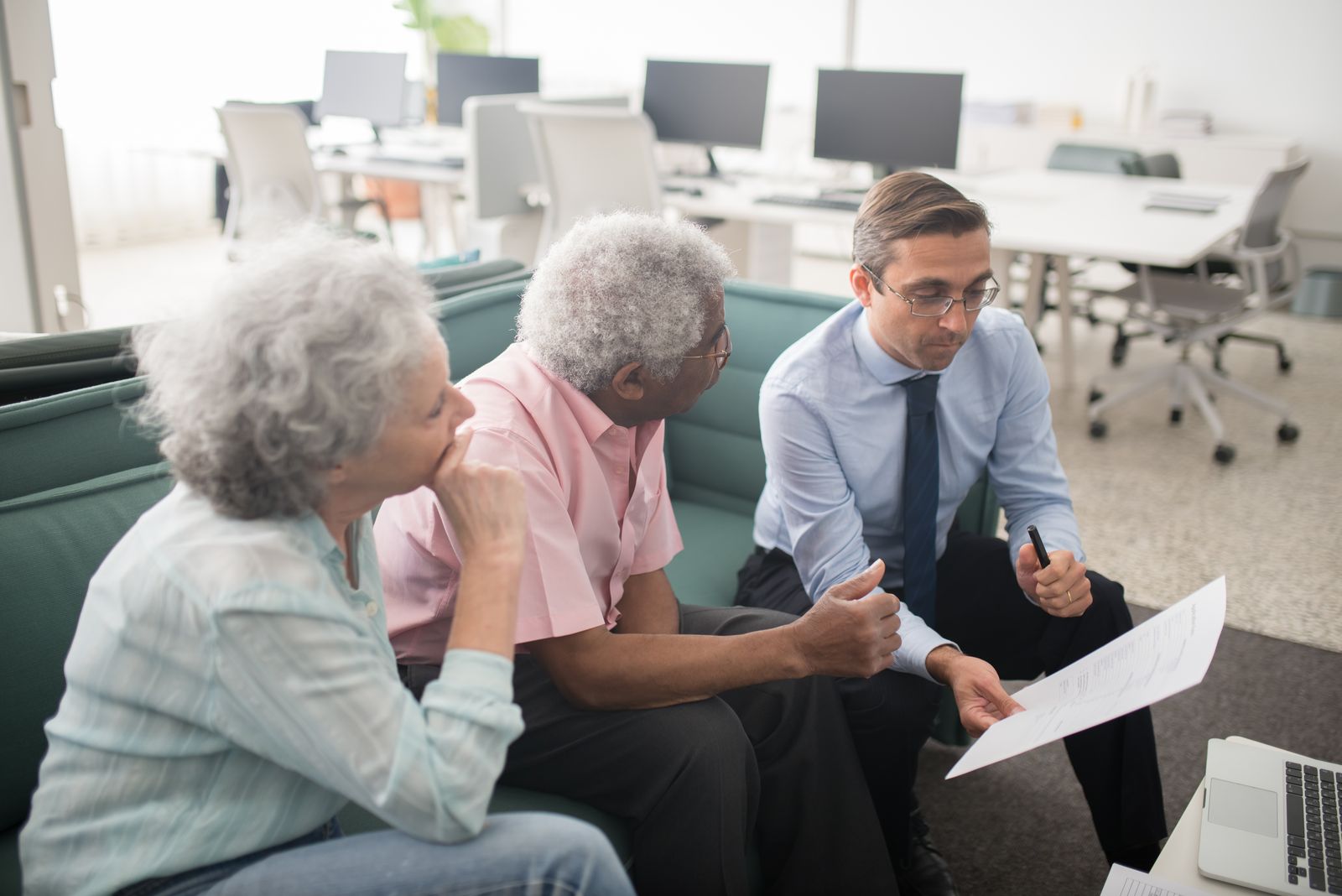 Senior couple on a couch discussing a document with a financial advisor